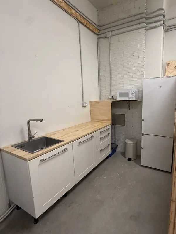 Kitchen at Espacio Remoto: wooden worktop with sink, microwave on its shelf and fridge